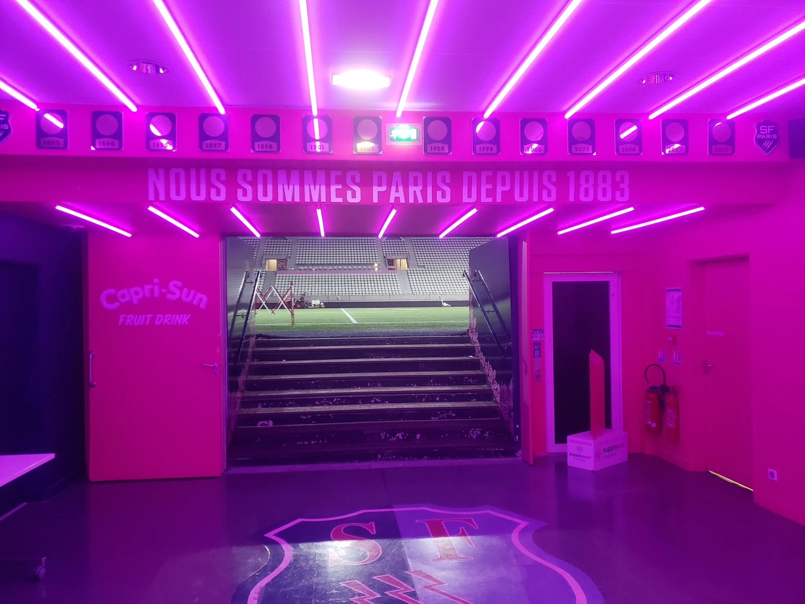 Couloir hospitalité rose néon du Stade Jean-Bouin avec l'inscription Nous sommes Paris depuis 1883