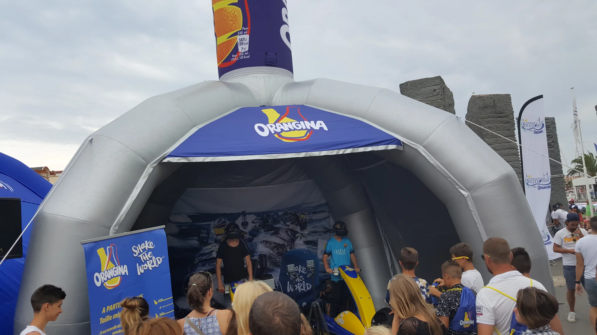 Dôme gonflable Orangina Shake the World sur le quai de Gruissan avec jet ski VR sous le chapiteau et foule en attente