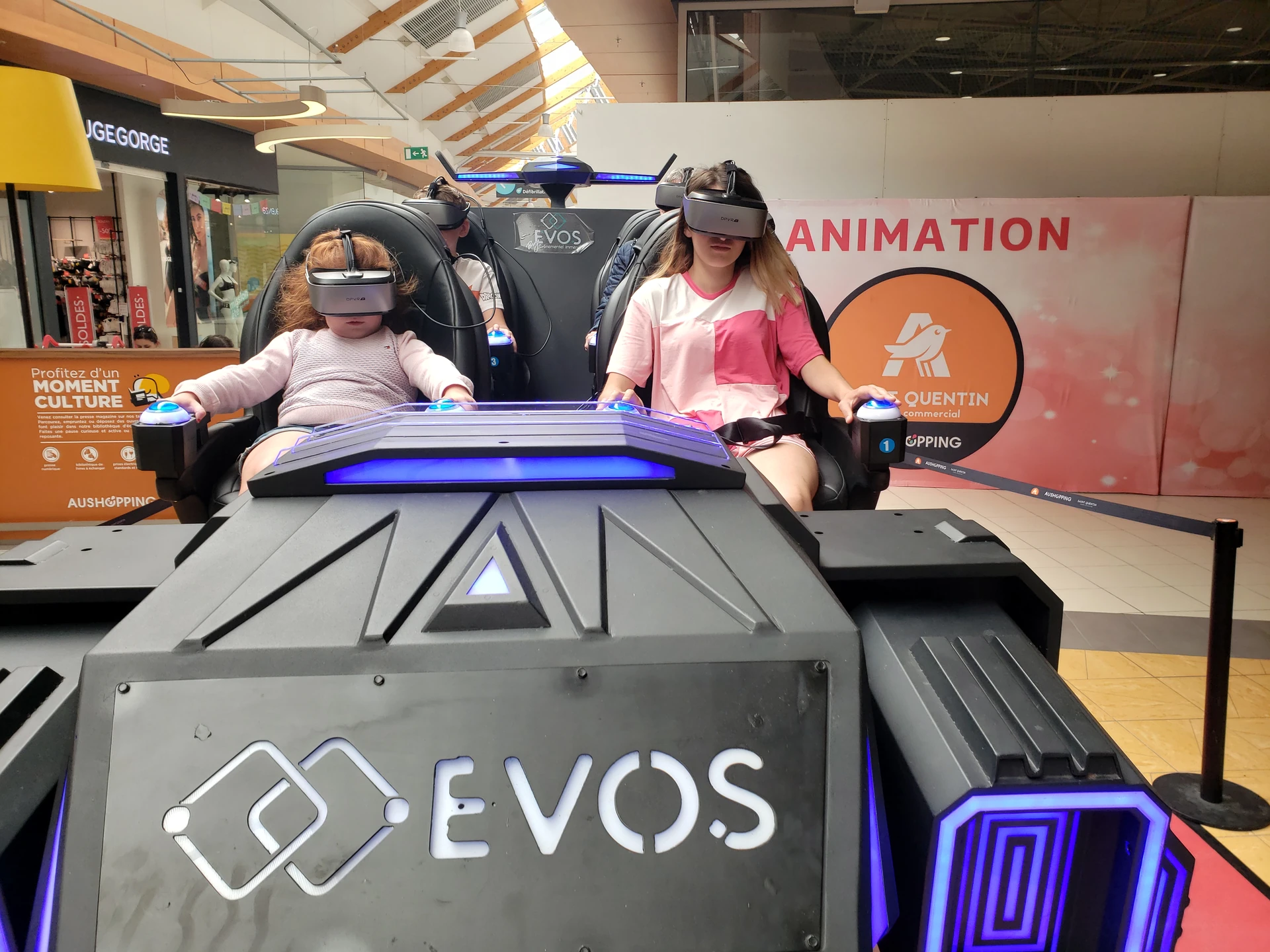 Mère et petite fille casque sur les yeux dans la navette Evos Sensation - kakemono Aushopping Saint-Quentin visible