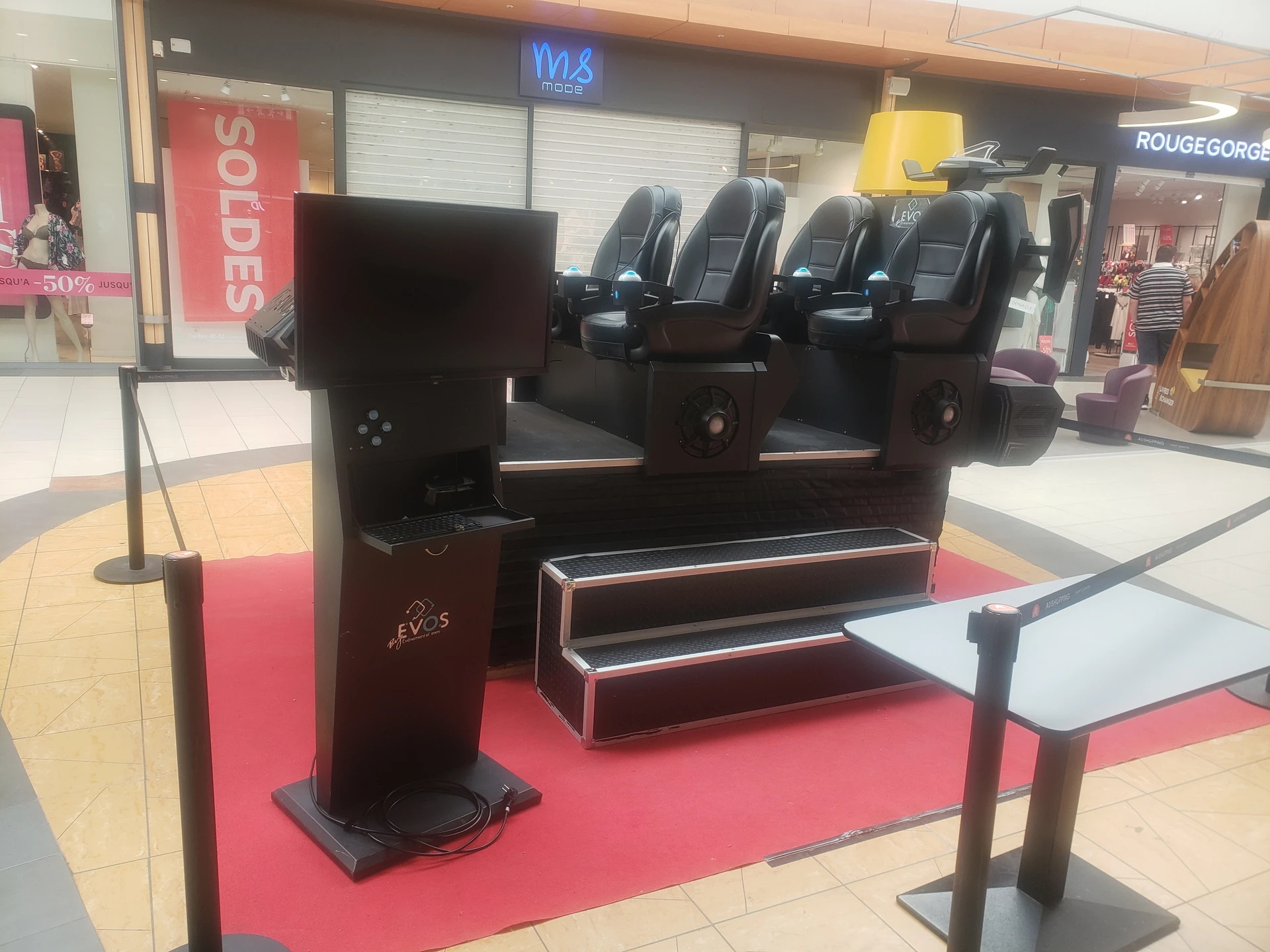 Navette VR Evos Sensation vue de profil avec borne d'expérience face aux boutiques M&S Mode et RougeGorge