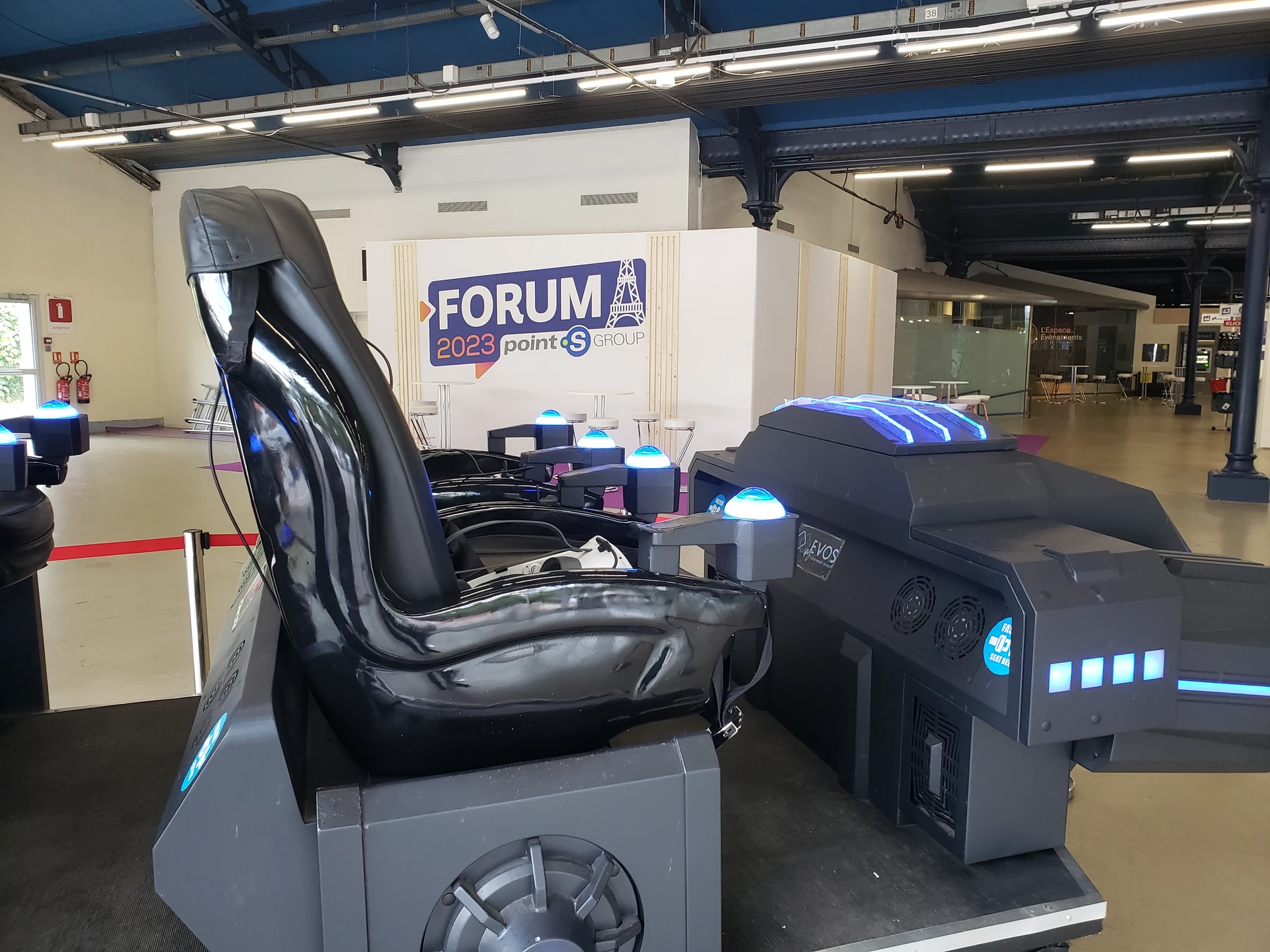Détail du siège baquet motorisé d'un simulateur Evos Sensation avec logo Evos visible, halle du forum parisien