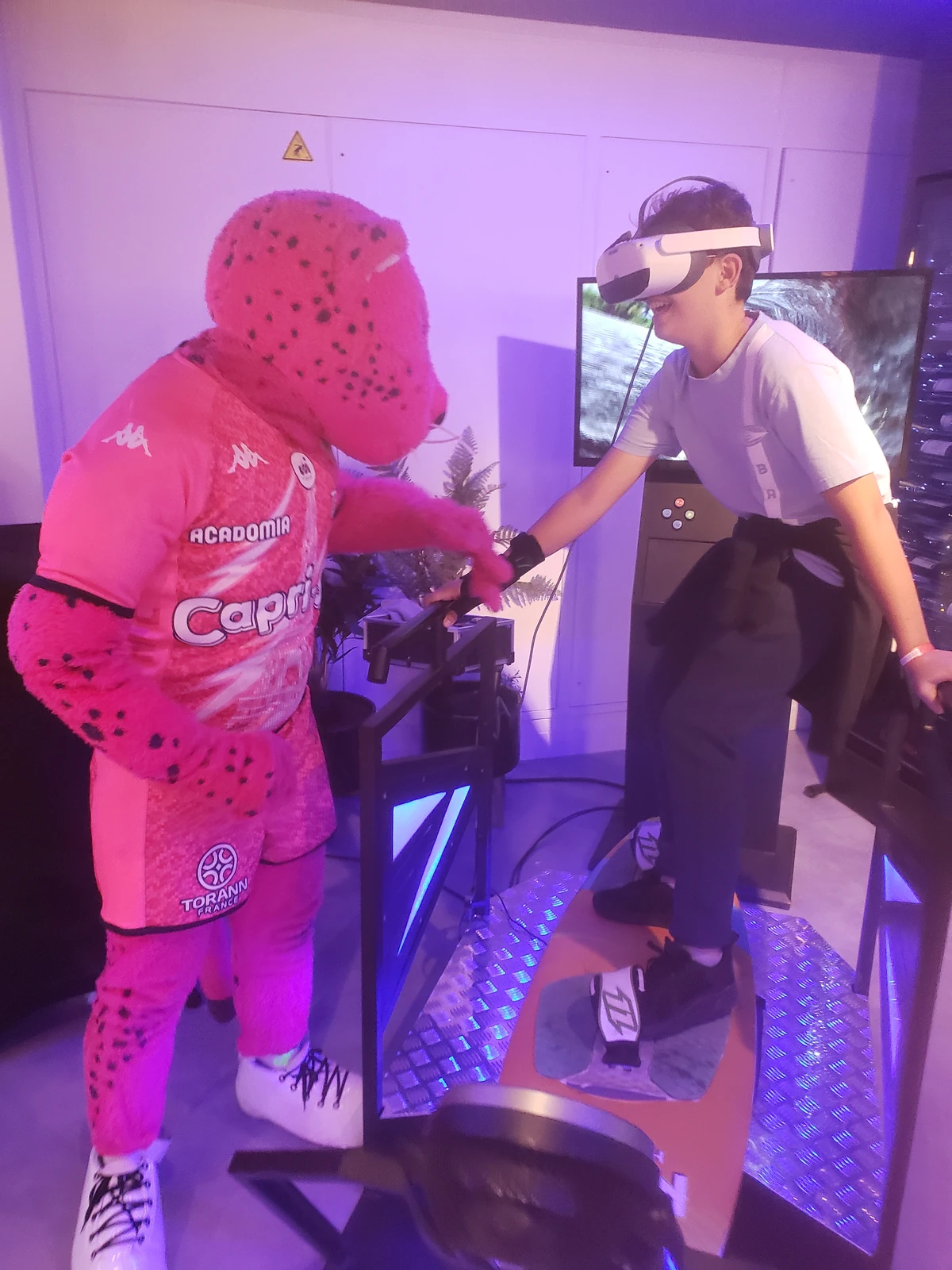 Enfant en casque VR sur simulateur surf et mascotte officielle Stade Français Paris en loge hospitalité