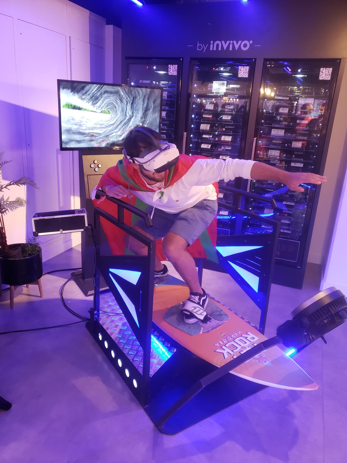 Invité en chemise blanche sur simulateur surf VR devant la cave InVivo en soirée de match