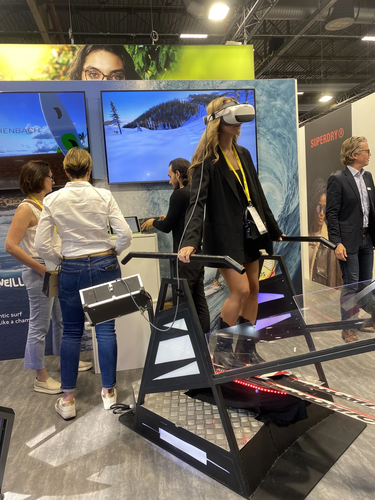 Visiteuse en blazer sur le simulateur surf VR du stand Eschenbach pendant le Silmo Paris 2023