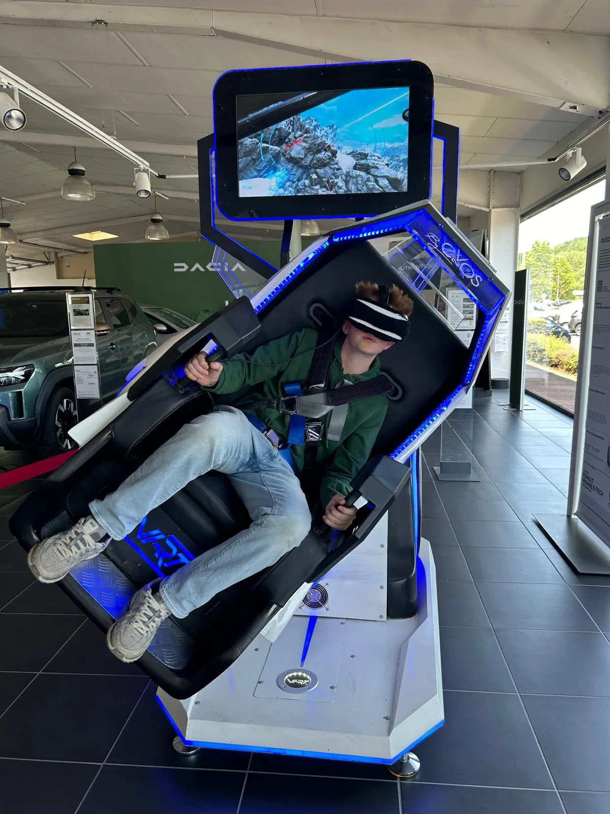 Jeune participant en rotation dans le simulateur Double 360 VR avec Dacia Duster visible côté showroom