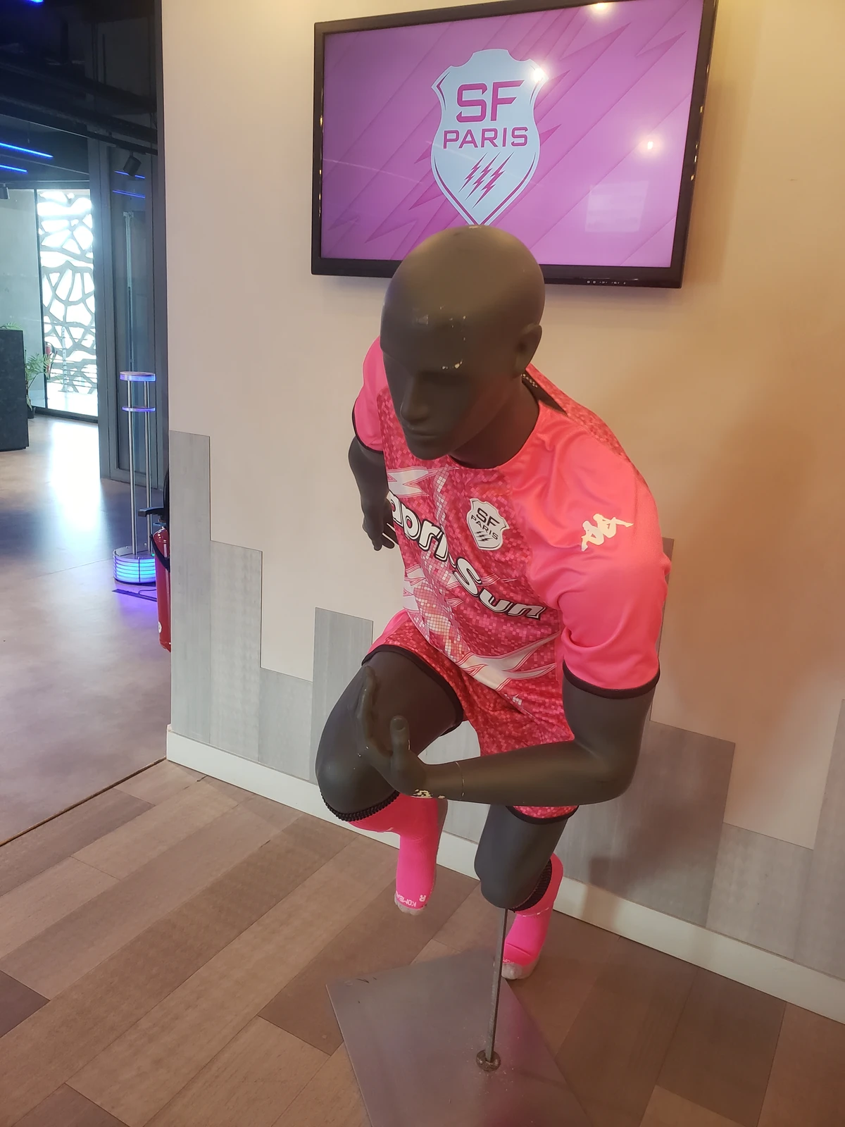 Mannequin en maillot rose Stade Français Paris devant un écran avec l'écusson SFP en salon hospitalité