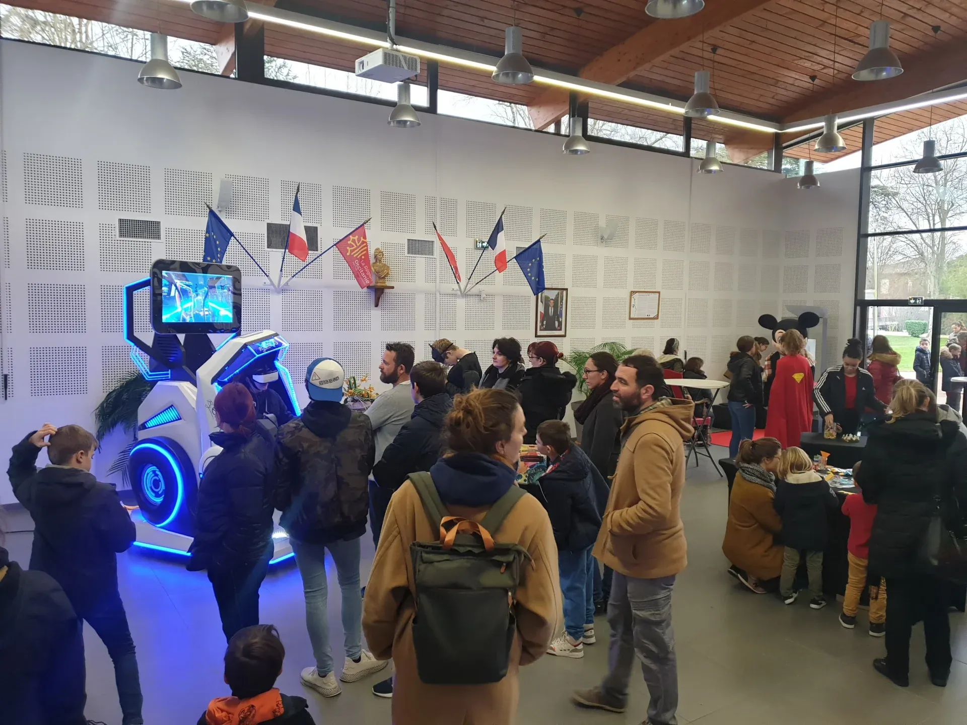 Familles et enfants autour d'un simulateur VR dans une salle municipale