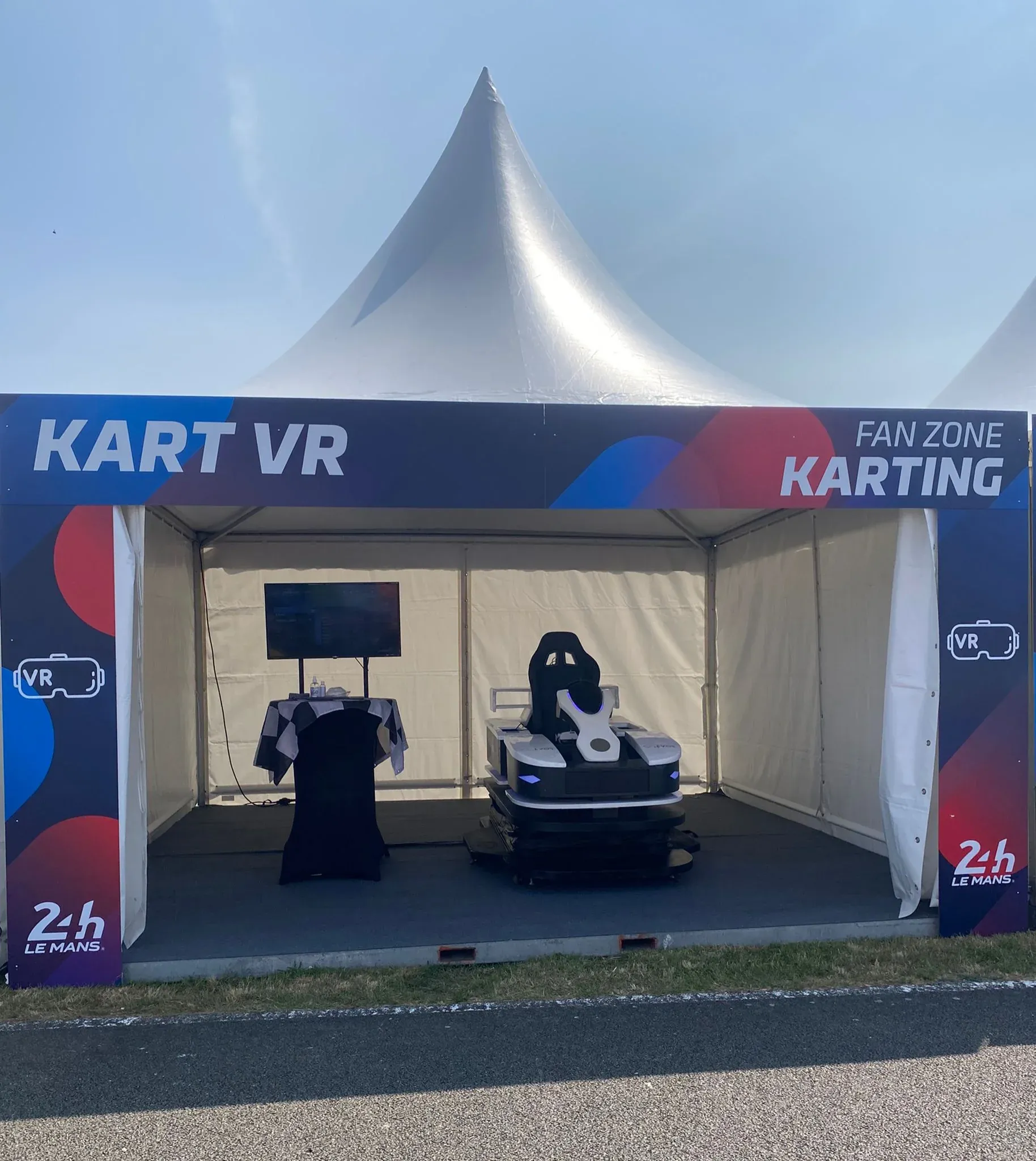 Stand Kart VR Fan Zone Karting aux 24 Heures du Mans avec simulateur Evos et écran sous tente pagode blanche
