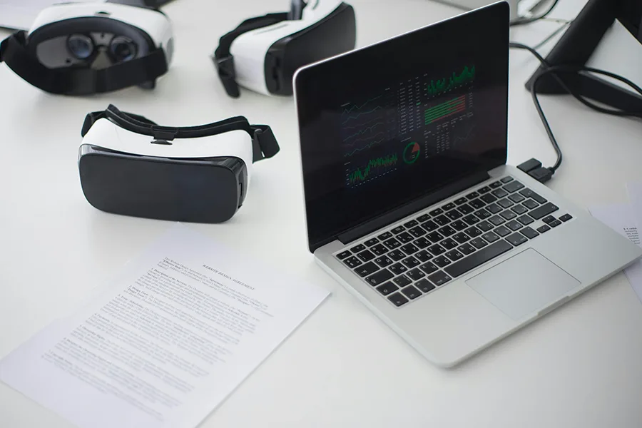 Ordinateur portable sur un bureau blanc avec deux casques VR et des documents