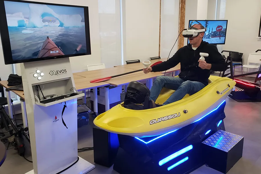 Simulateur VR en forme de kayak jaune avec écran affichant un parcours nautique