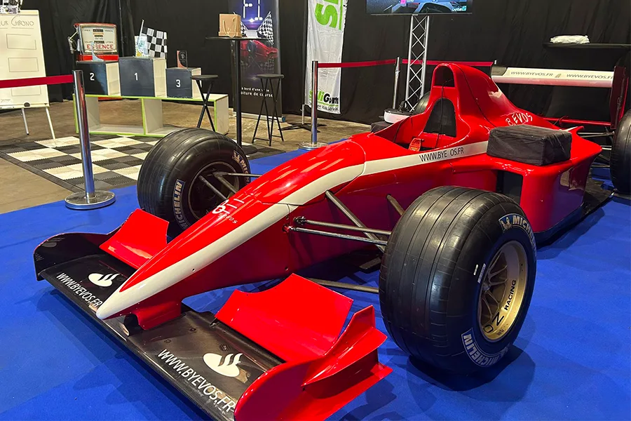 Simulateur de Formule 1 rouge grandeur nature exposé sur un stand professionnel
