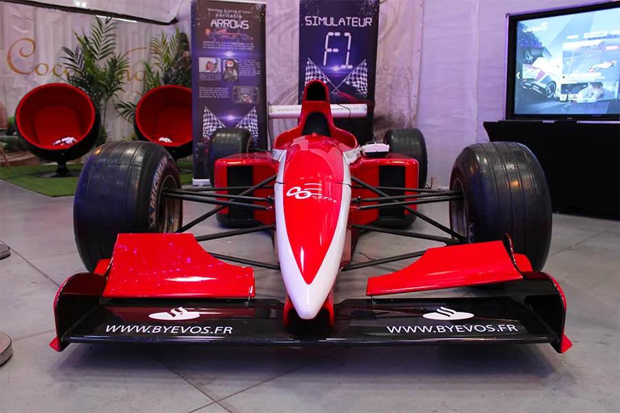 Simulateur F1 By Evos vu de face avec écran de course et sièges sur un stand événementiel