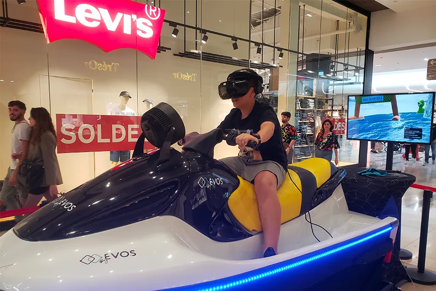 Personne portant un casque VR sur un simulateur jet ski By Evos installé dans un magasin