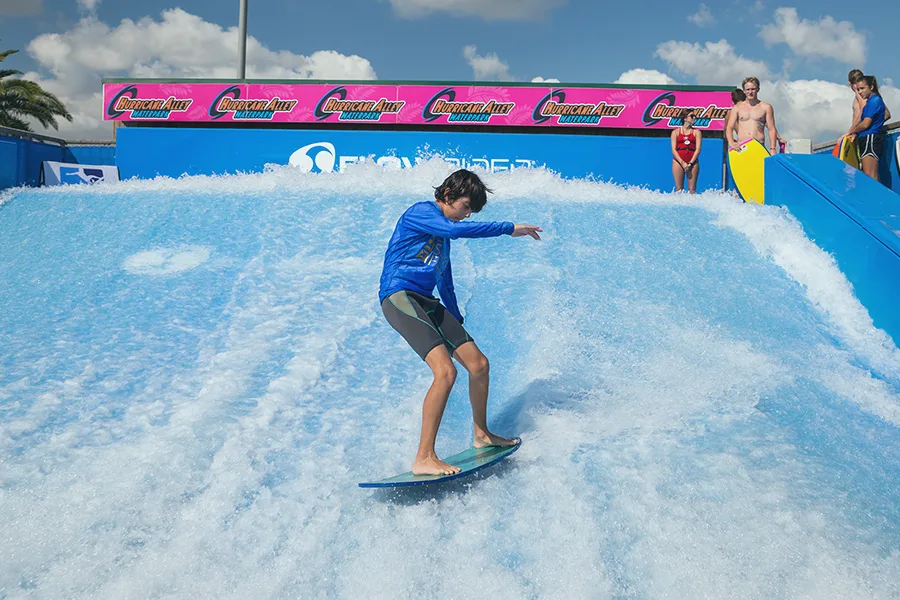 Surfeur glissant sur une vague artificielle FlowRider en extérieur