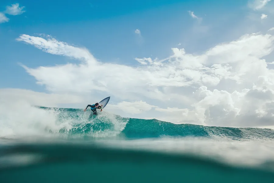 Surfeur en equilibre sur une vague en pleine mer vu depuis la surface