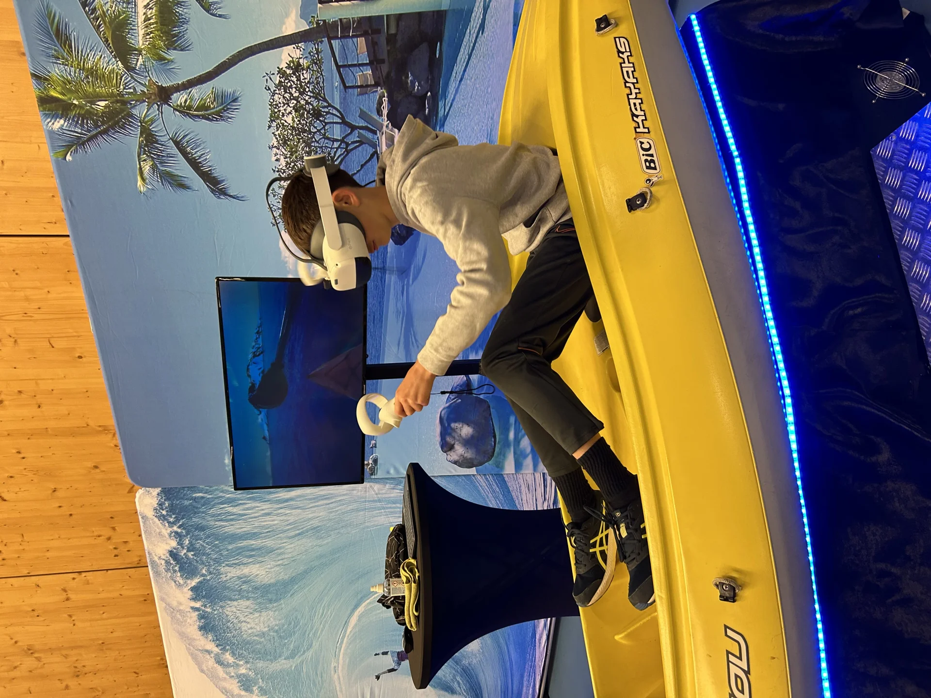 Jeune participant casqué pagayant sur le simulateur de kayak en réalité virtuelle